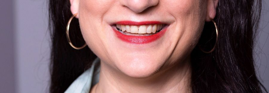 Lächelnde Person mit langen, dunklen Haaren